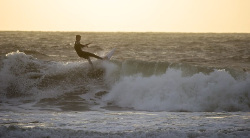 A Man Riding A Wave On Top Of A Surfboard