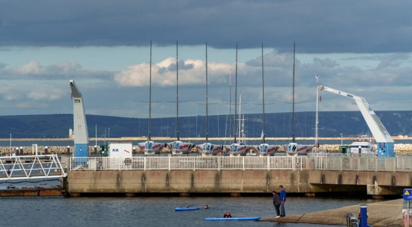 A Man Standing On A Pier Next To A Body Of Water
