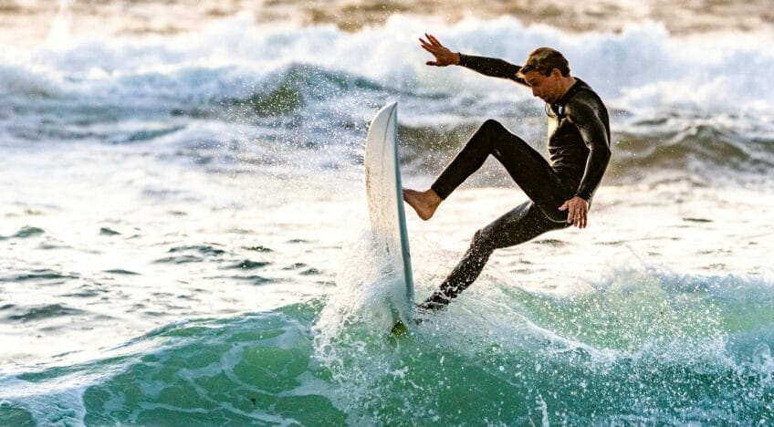 Energetic surfer performing a trick on ocean waves, showcasing skill and excitement.