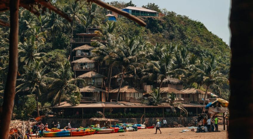 Explore a tropical beach scene with palm trees, kayaks, and a hillside resort. Perfect summer getaway.
