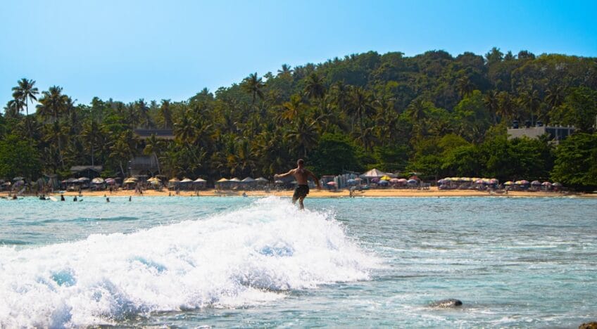 Um Surfista Surfa Uma Onda Perto De Uma Praia Tropical MoElKxO0wuM